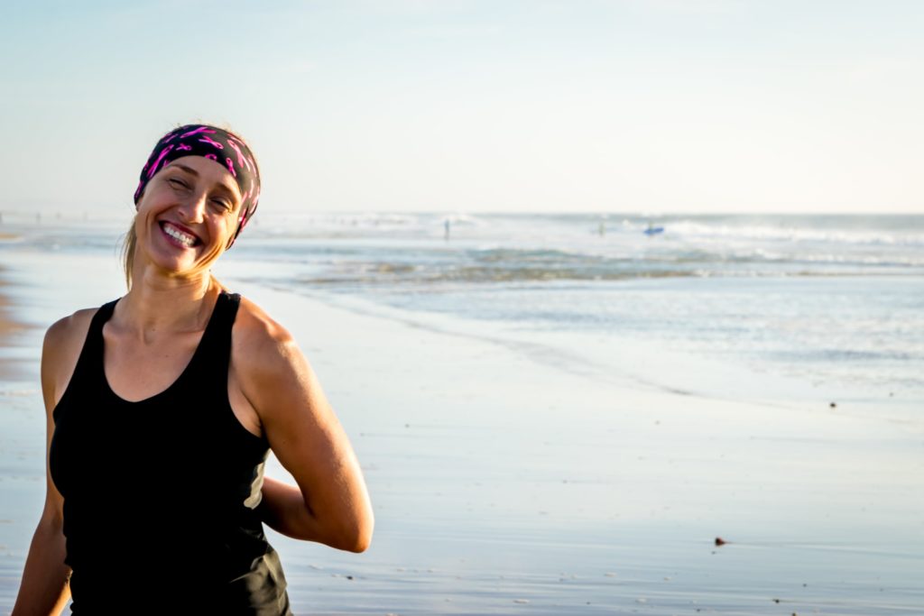 femme atteinte d'un cancer qui porte un foulard et qui sourit sur une plage