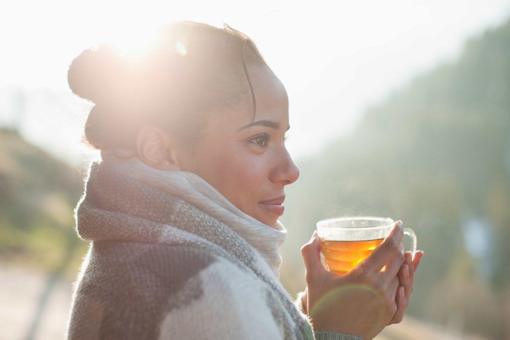 Gros plan de souriant Femme buvant du thé en plein air pour booster son immunité naturelle